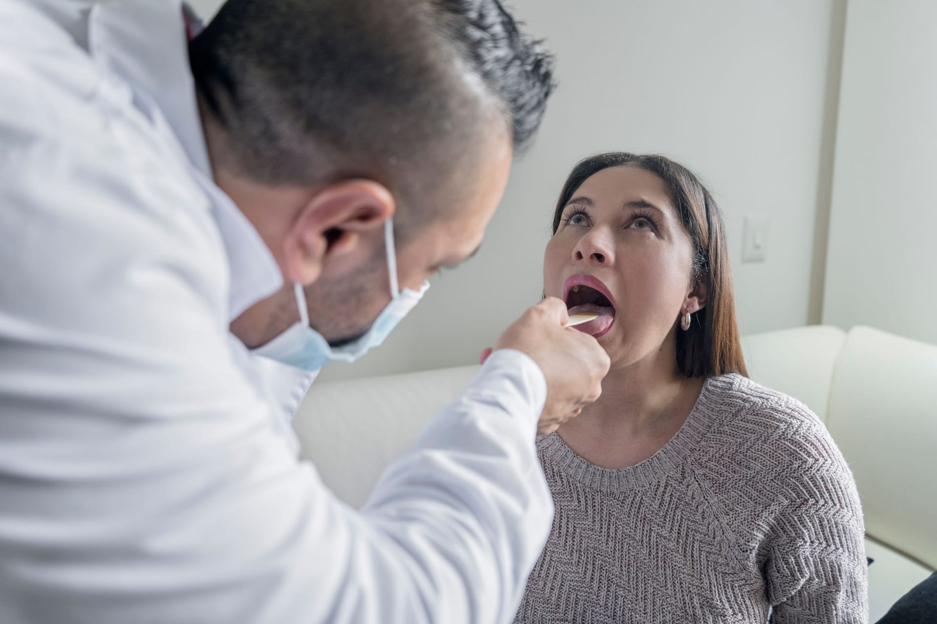 Arzt begutachtet den Rachen einer Patientin (Symbolbild): Zungenveränderungen sind in vielen Fällen harmlos.