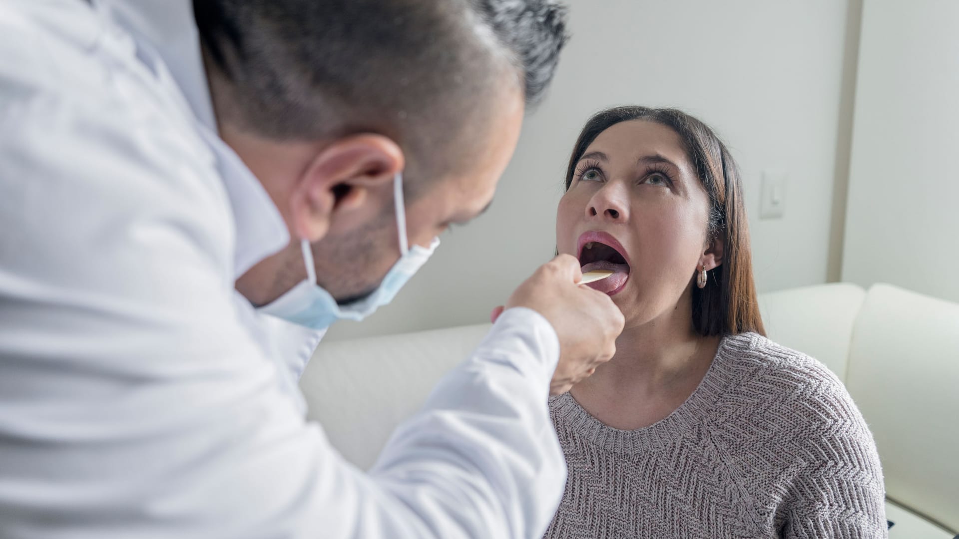 Arzt begutachtet den Rachen einer Patientin (Symbolbild): Zungenveränderungen sind in vielen Fällen harmlos.