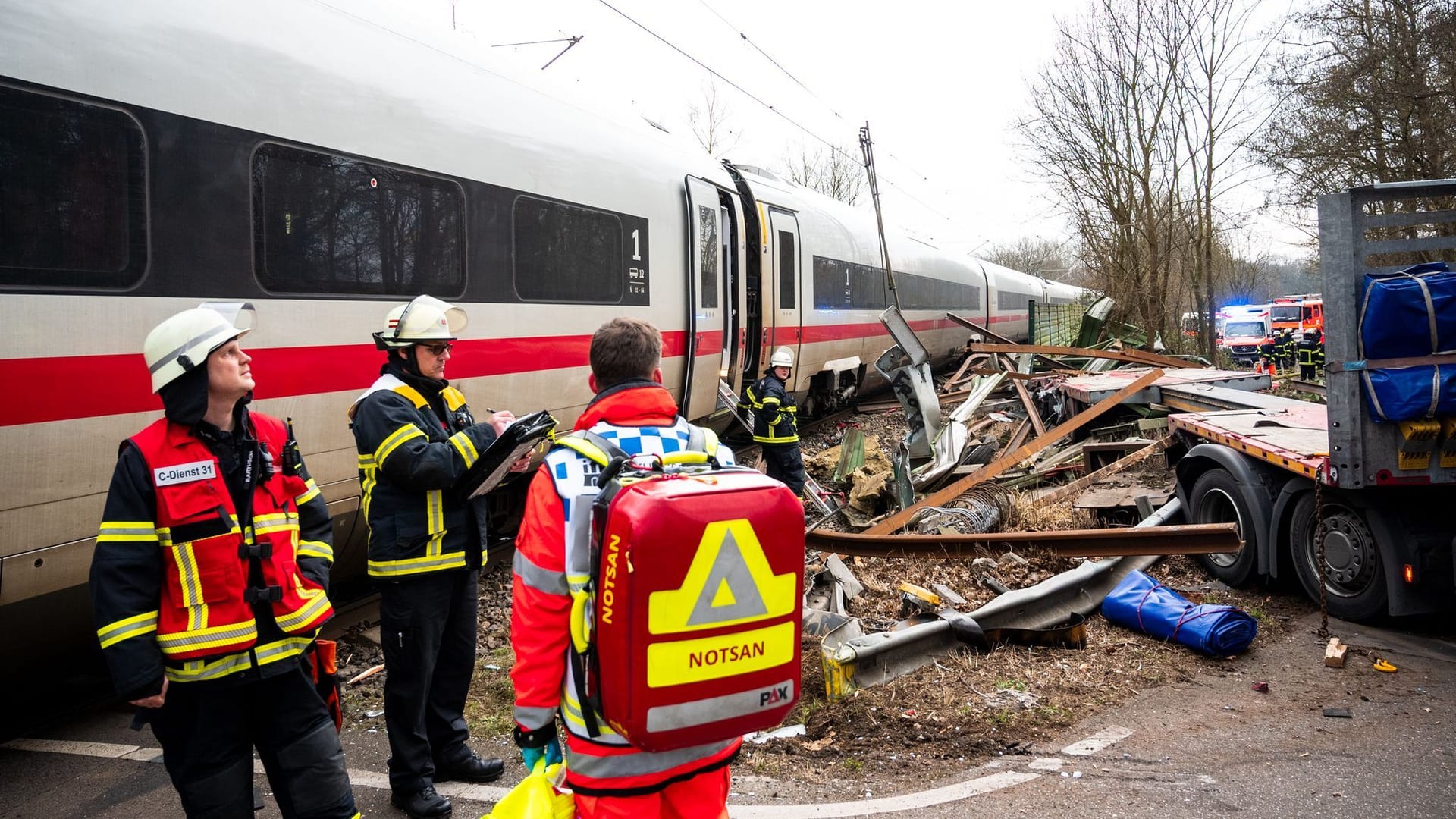 Ein Trümmerfeld in Rönneburg: Einsatzkräfte stehen an der Unfallstelle an einem Bahnübergang.