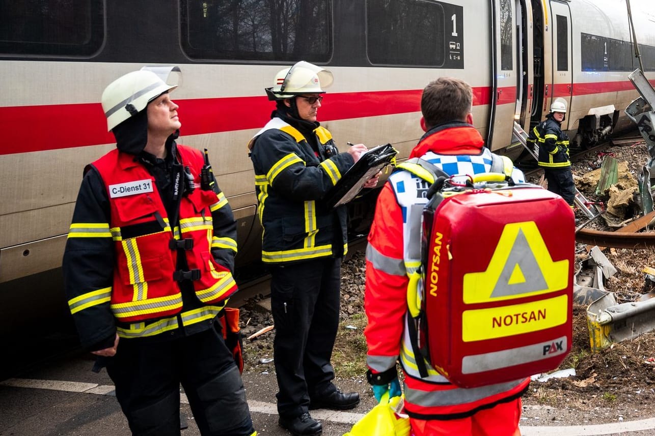 Ein Trümmerfeld in Rönneburg: Einsatzkräfte stehen an der Unfallstelle an einem Bahnübergang.