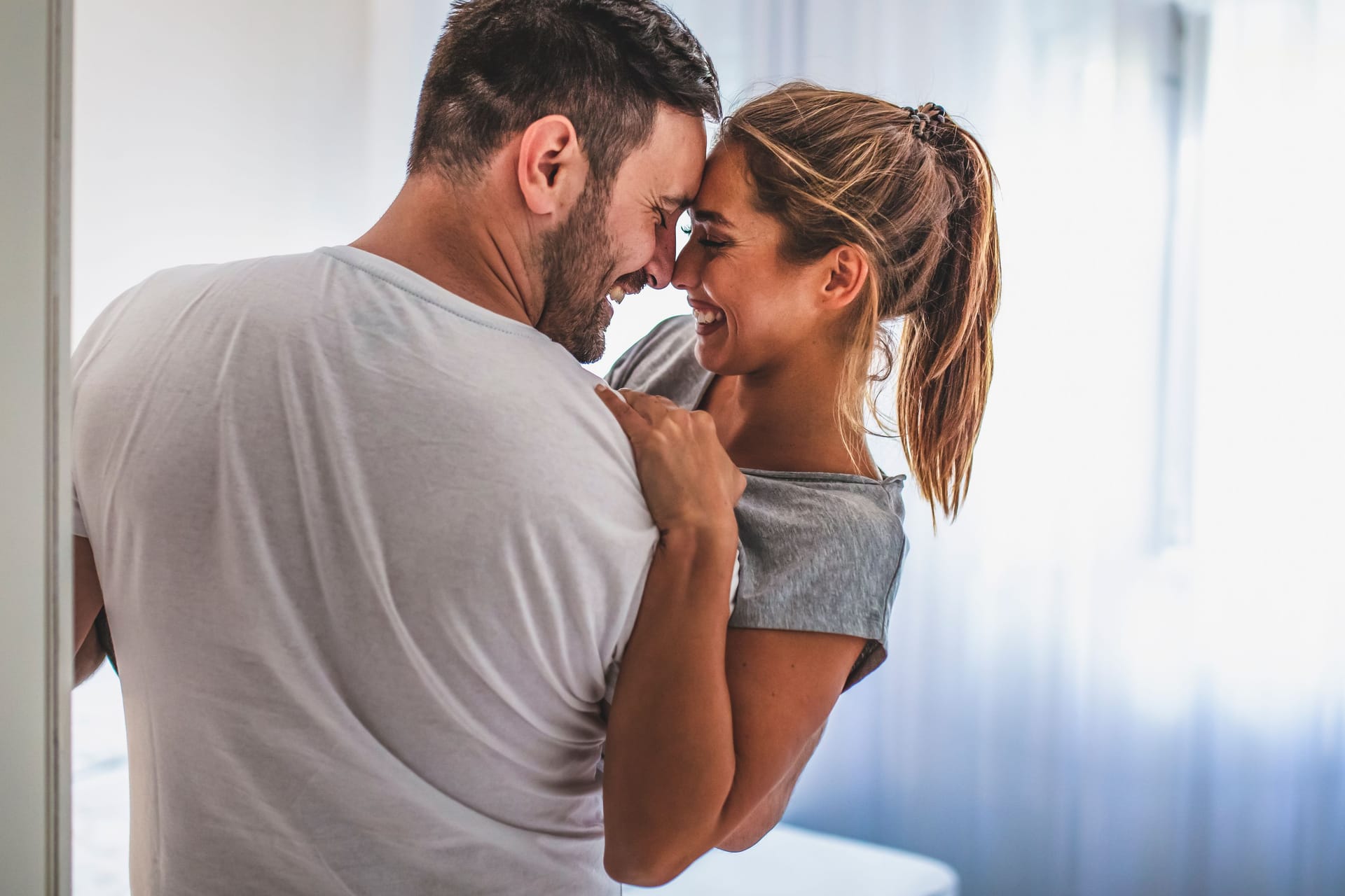 Ein Mann trägt eine lachende Frau in ein Zimmer