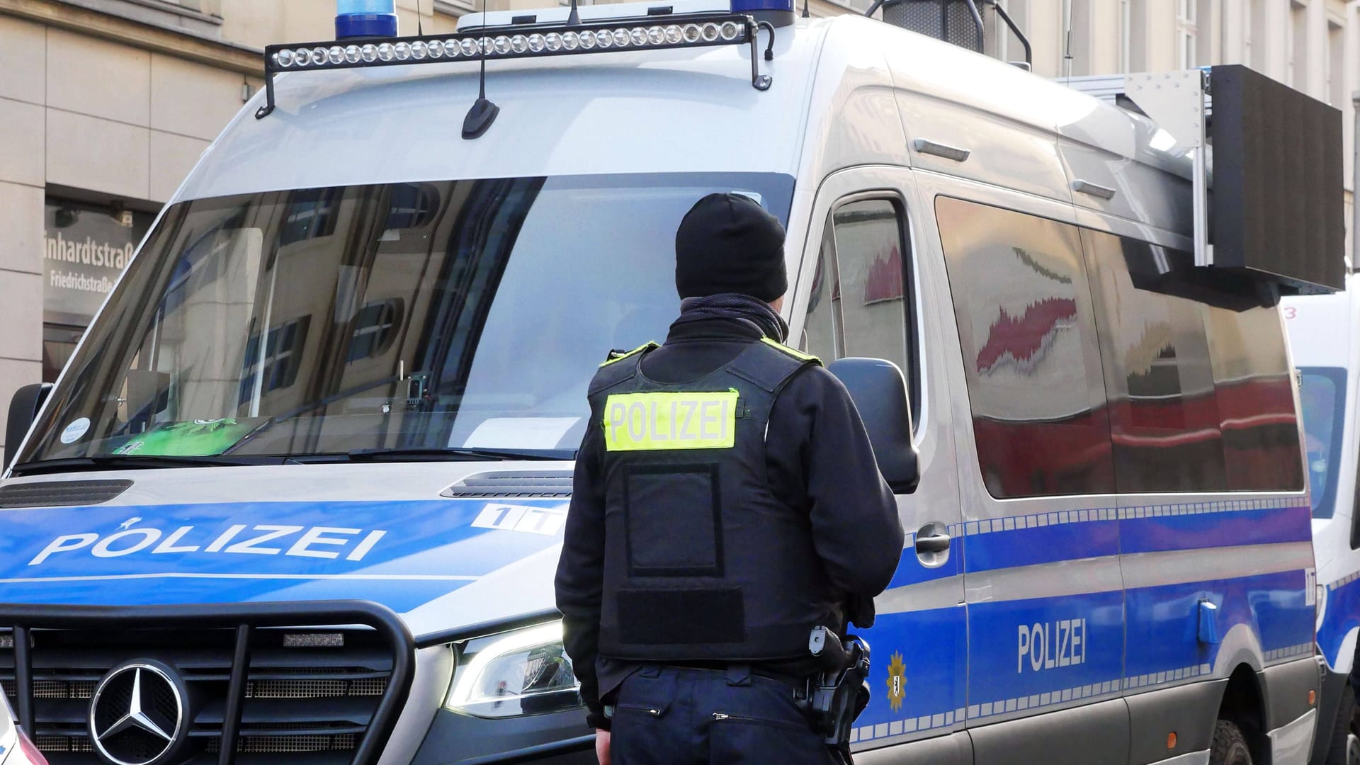 Polizist vor Polizeiauto (Symbolbild): Der Mann schubste einen Polizisten und Schlug ihm ins Gesicht.