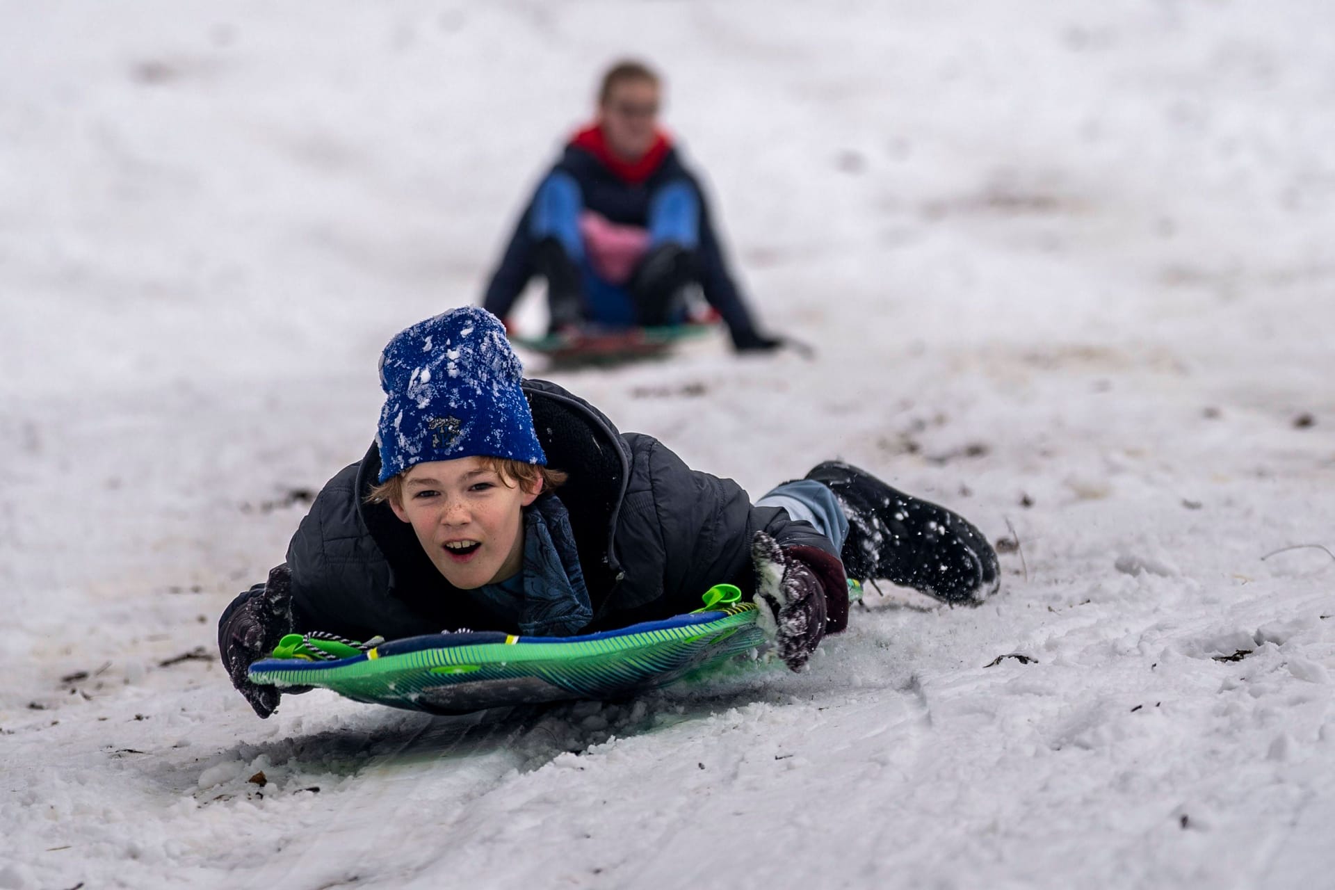 Kinder beim Rodeln (Symbolbild): In einigen Regionen fällt noch einmal Schnee.