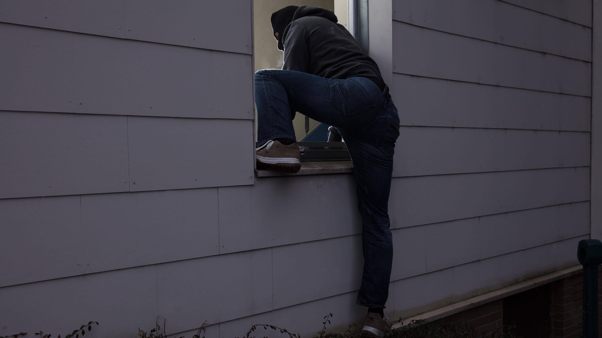 Einbrecher dringt durch ein Fenster ins Haus ein (Symbolbild): Die Tatverdächtigen stammen aus Bayern und Schleswig-Holstein.