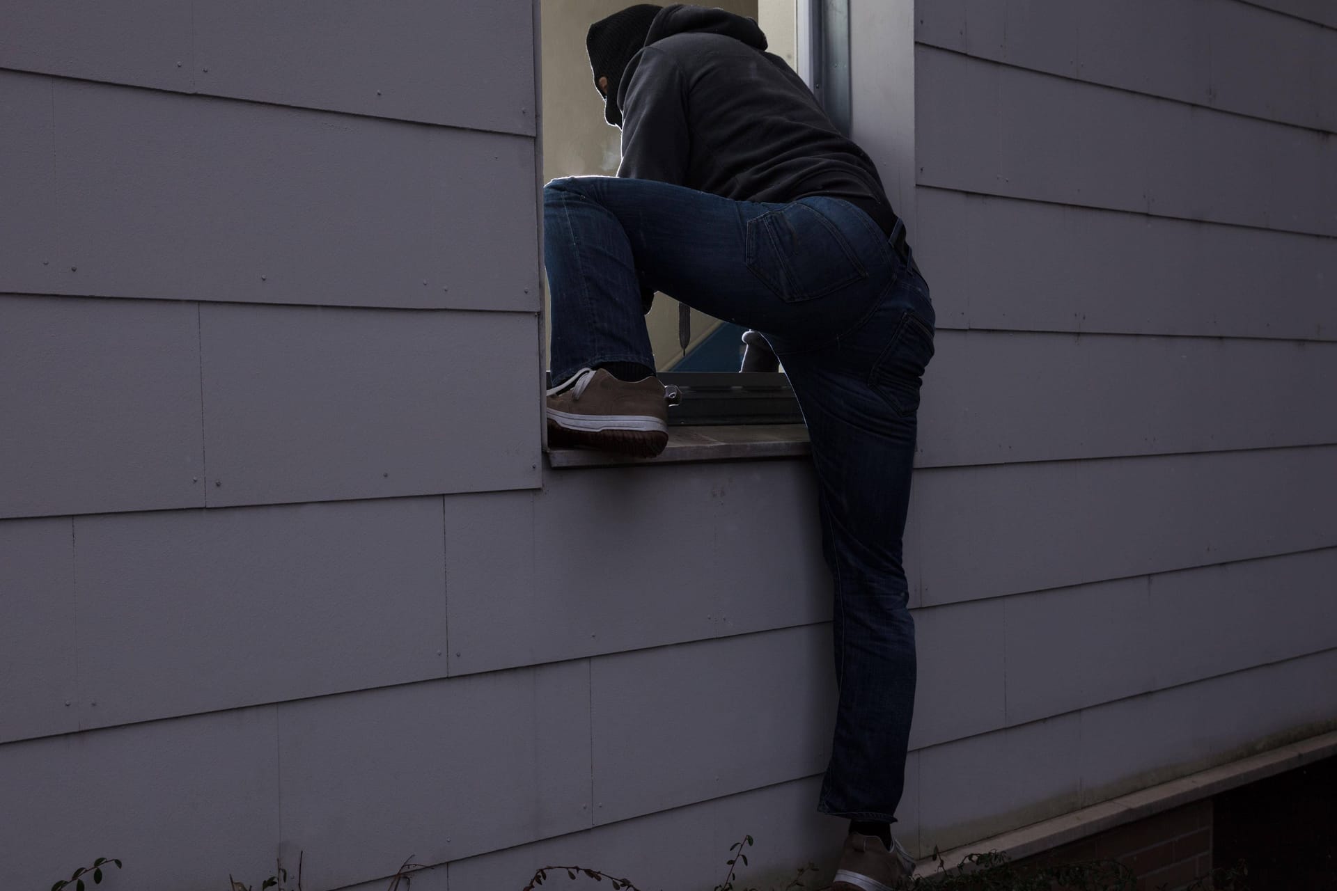 Einbrecher dringt durch ein Fenster ins Haus ein (Symbolbild): Die Tatverdächtigen stammen aus Bayern und Schleswig-Holstein.