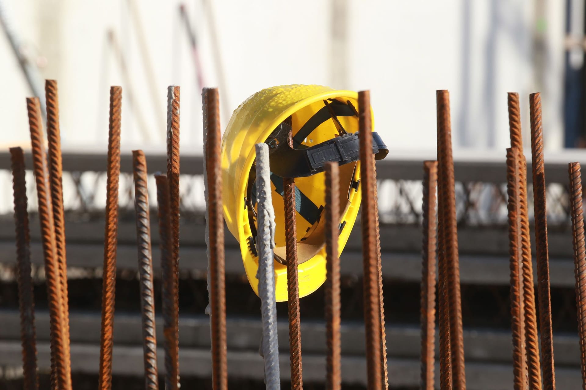 Ein Helm hängt an einer Baustelle (Symbolbild): Auch auf dem Bau wird geeignetes Personal händeringend gesucht.