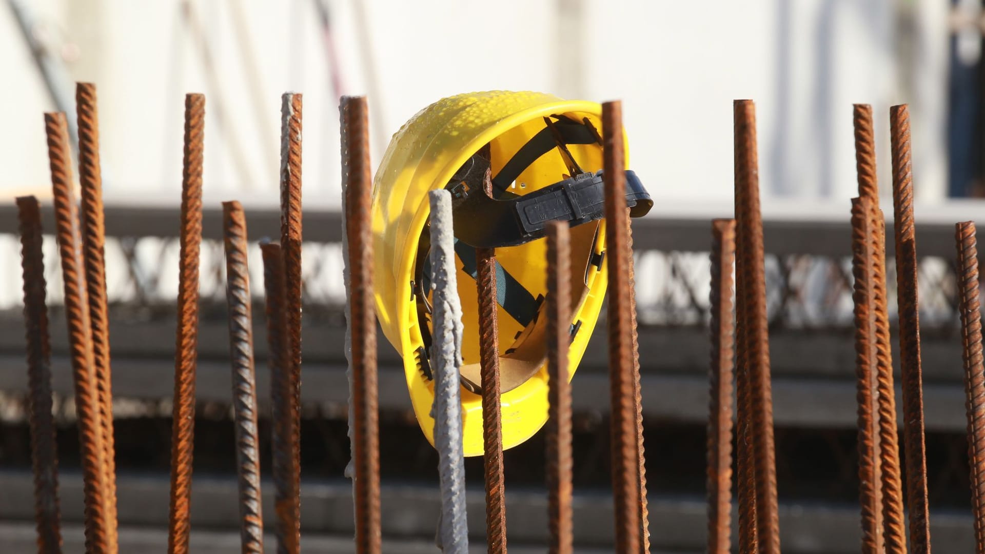 Ein Helm hängt an einer Baustelle (Symbolbild): Auch auf dem Bau wird geeignetes Personal händeringend gesucht.