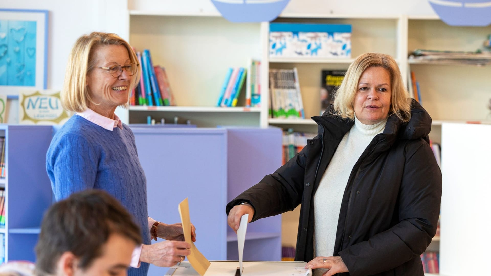 Nancy Faeser (SPD, rechts), Bundesinnenministerin, gibt in einem Wahllokal ihre Stimme ab.