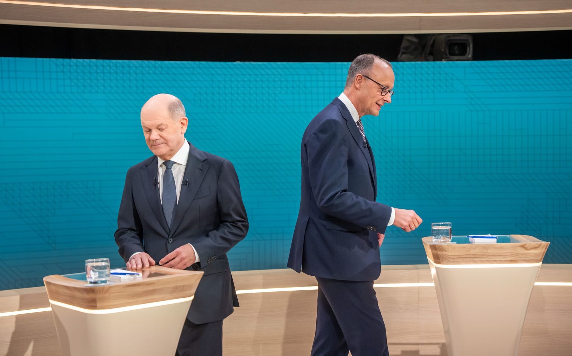 Der Beginn des Duells: Olaf Scholz (l) und Friedrich Merz treten an ihre Tische.