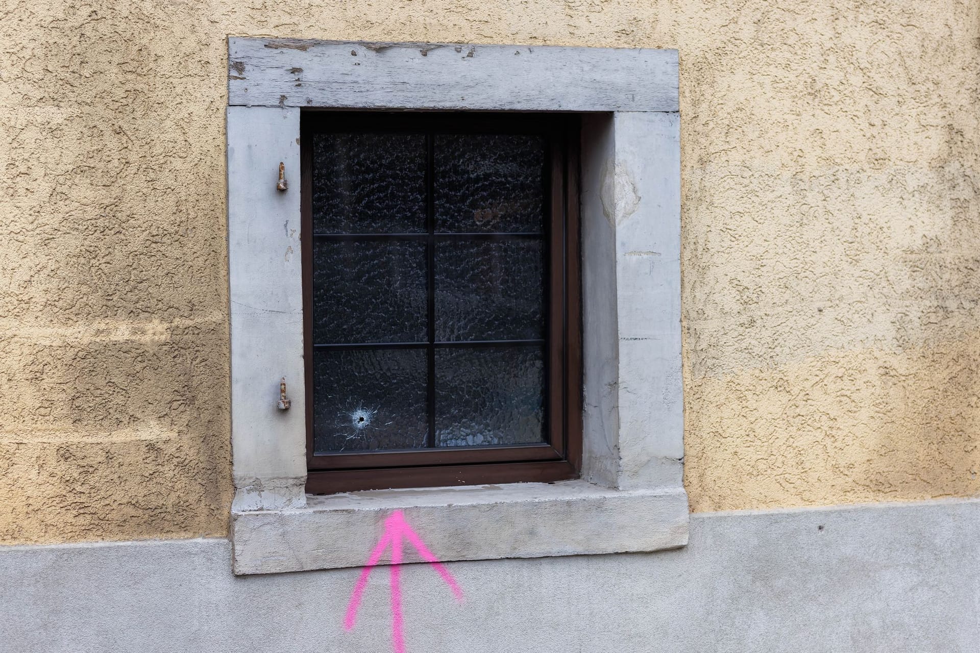 Eichstetten am Kaiserstuhl: Ein mit Farbe gesprühter Pfeil der Kriminaltechnik weist auf ein Einschussloch in einem Fenster hin. Polizisten haben dort in der Nacht auf einen Mann geschossen.