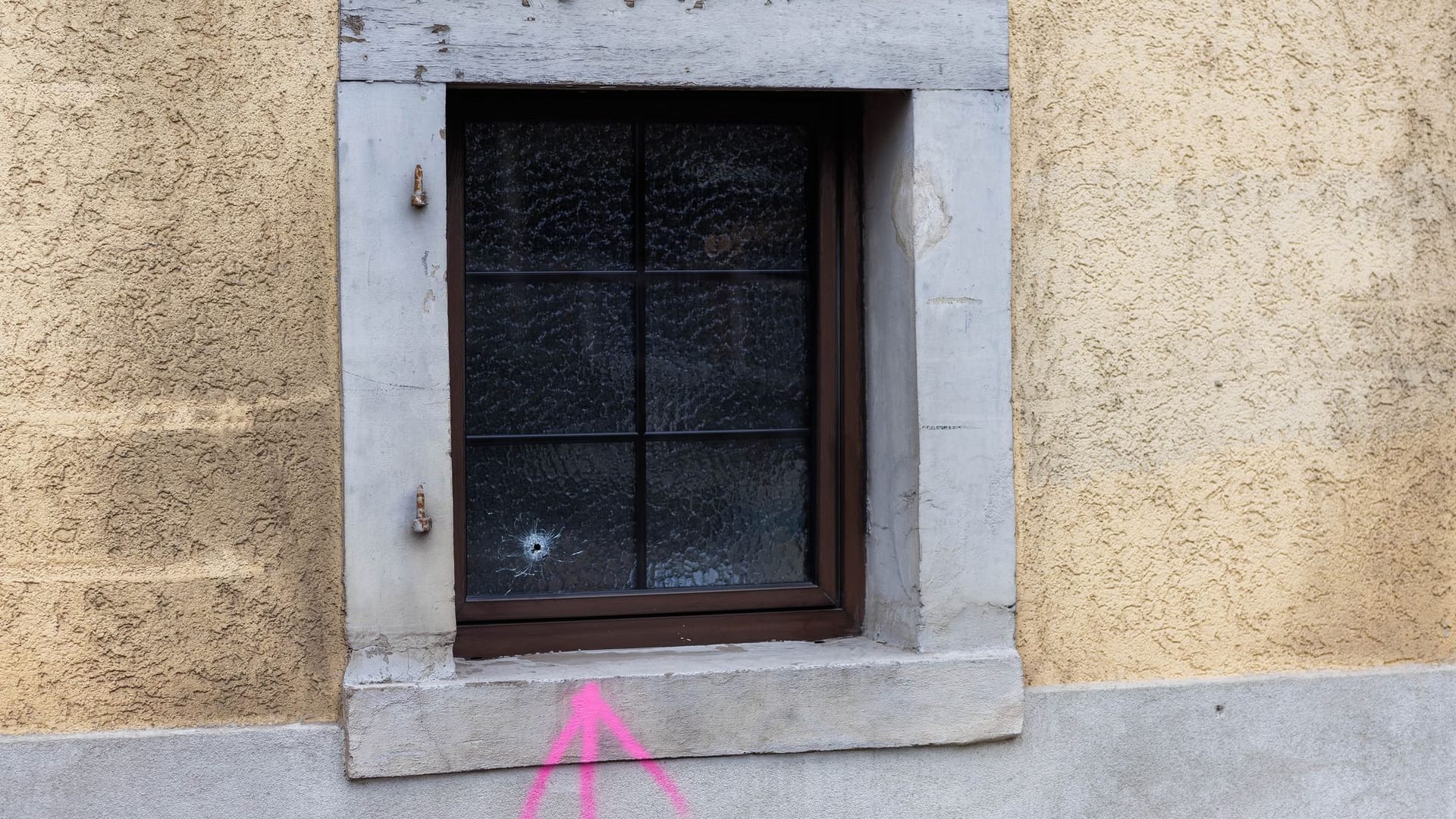 Eichstetten am Kaiserstuhl: Ein mit Farbe gesprühter Pfeil der Kriminaltechnik weist auf ein Einschussloch in einem Fenster hin. Polizisten haben dort in der Nacht auf einen Mann geschossen.