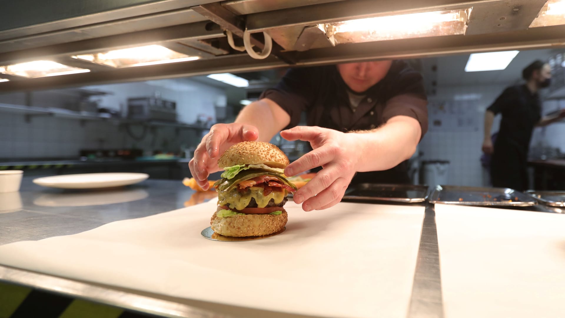 Ein Burger wird in einem Restaurant zubereitet (Symbolbild).