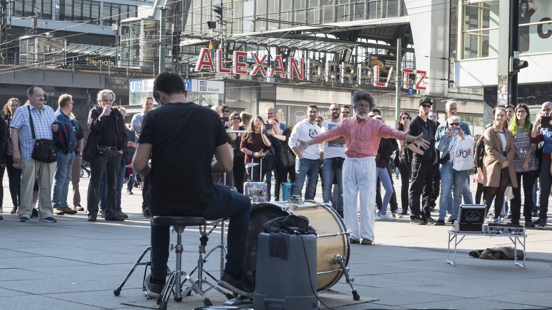 Straßenmusiker auf dem Berliner Alexanderplatz animiert mit seiner Musik einen Zuhörer zum Tanzen.