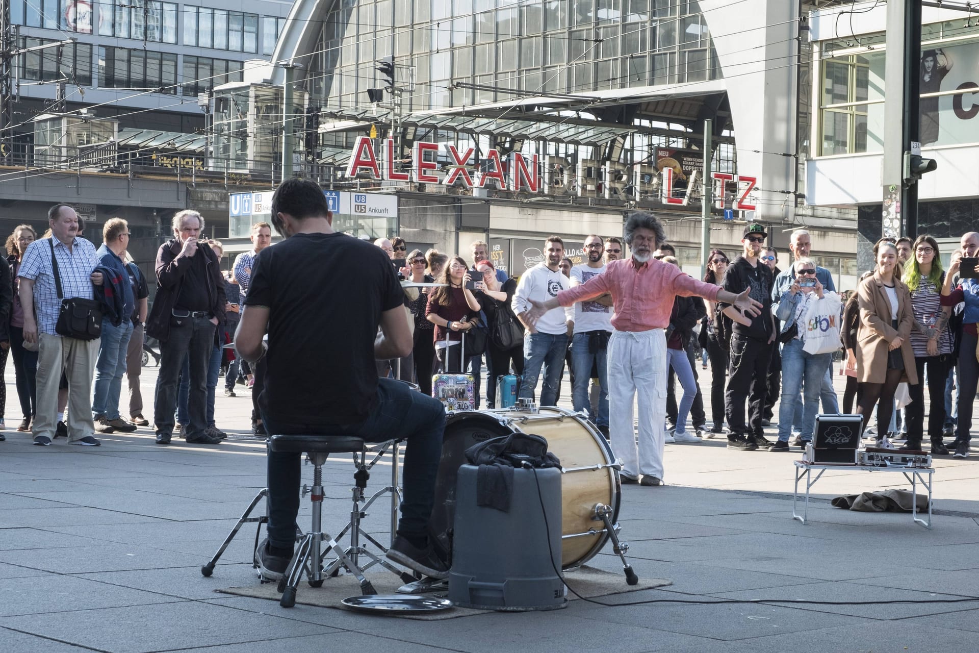 Straßenmusiker auf dem Berliner Alexanderplatz animiert mit seiner Musik einen Zuhörer zum Tanzen.