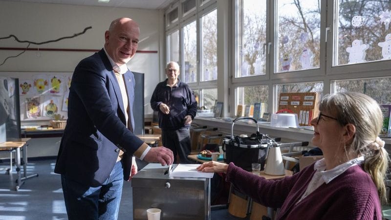 Kai Wegner (CDU, links), Regierender Bürgermeister von Berlin, gibt in seinem Wahllokal seine Stimme ab.