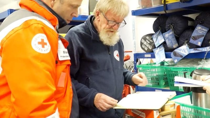 Mario Czaja (l), Präsident des DRK-Landesverbandes Berlin, und Wärmebusfahrer Herbert und Julia packen die Sachen für die Fahrt ein.