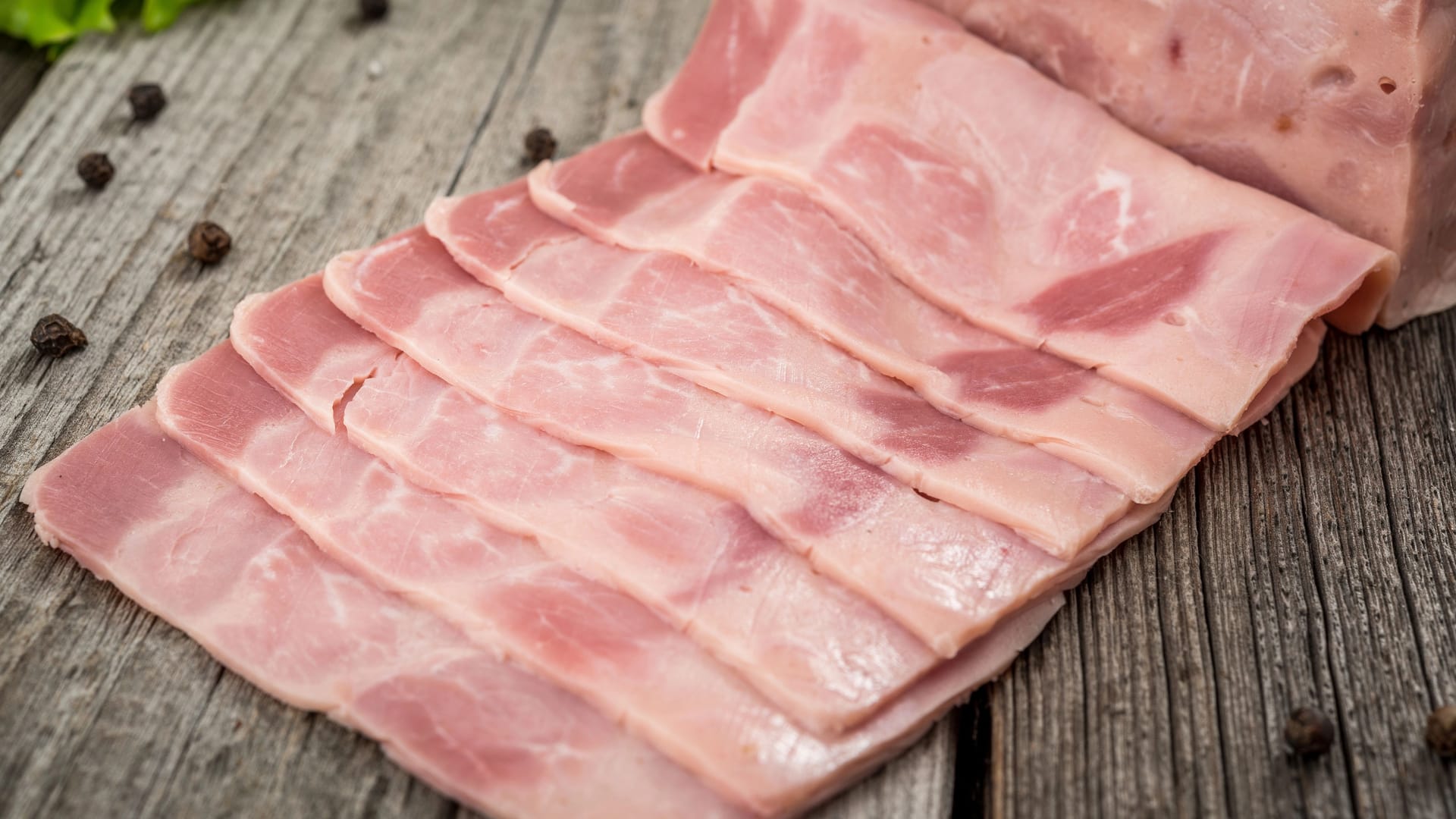 Cut sausage from ham on a wooden background