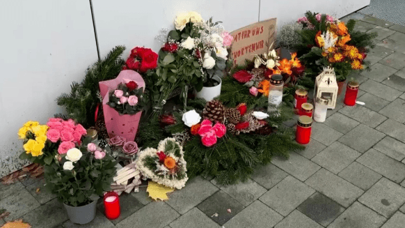 Blumen und Kerzen stehen vor einem Hauseingang in Erinnerung an die Opfer.