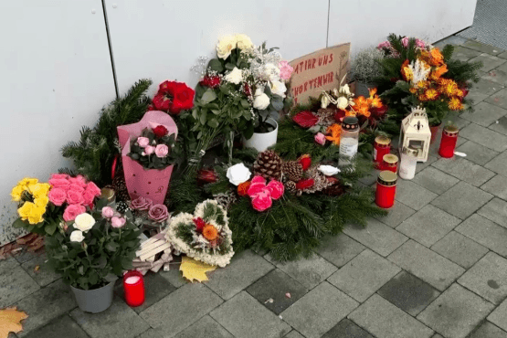 Blumen und Kerzen stehen vor einem Hauseingang in Erinnerung an die Opfer.