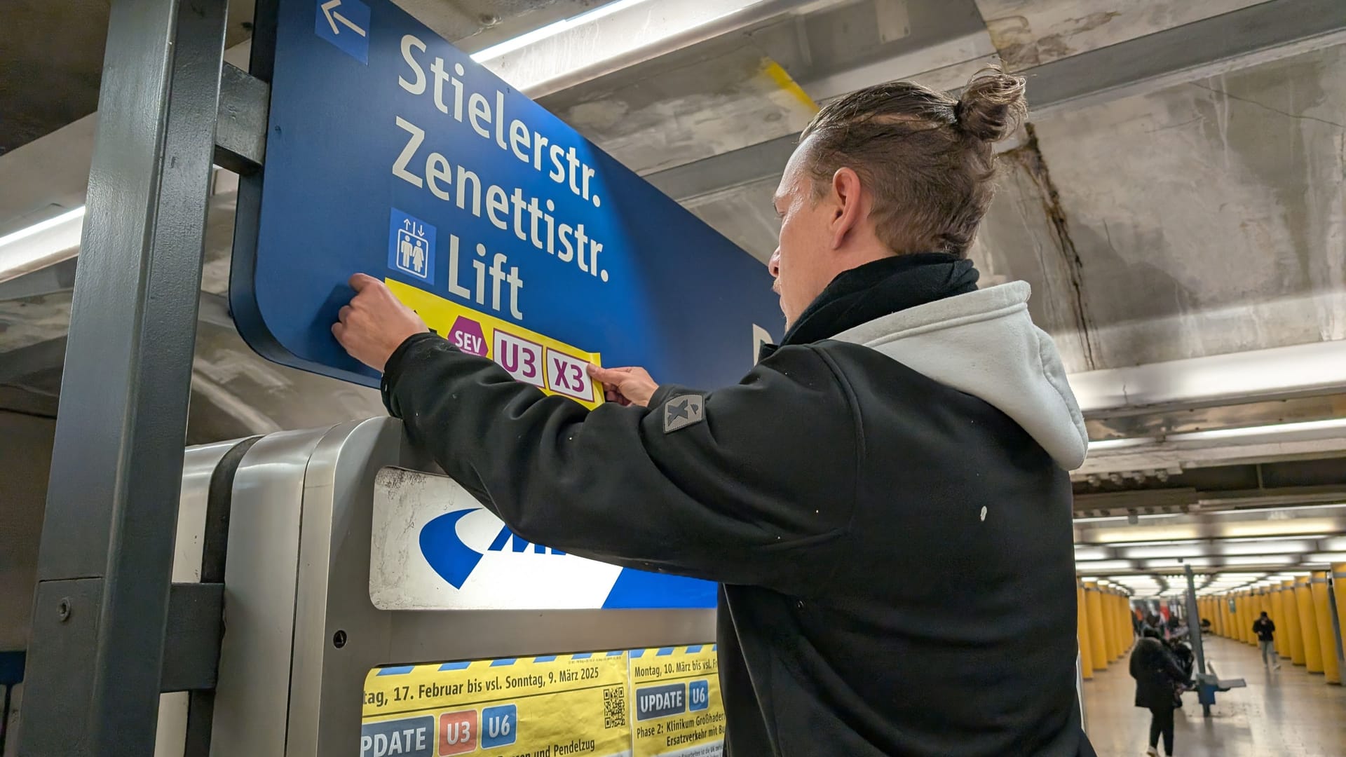 Ein MVG-Mitarbeiter bringt einen Aufkleber an, mit dem auf die anstehenden Bauarbeiten und den Ersatzverkehr aufmerksam gemacht werden soll.