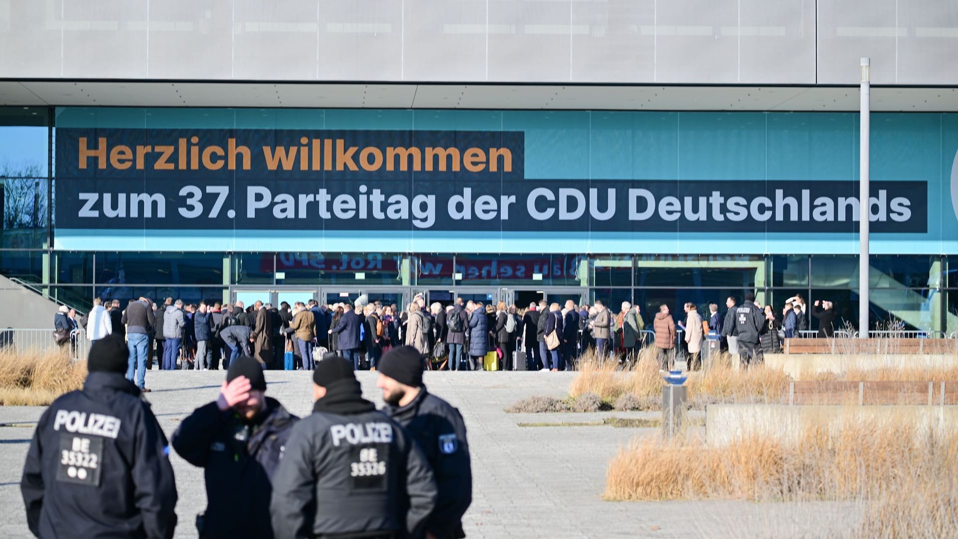 Polizeibeamte stehen vor Beginn des 37. Bundesparteitag der CDU im CityCube Berlin vor Teilnehmern, die in das Gebäude möchten.