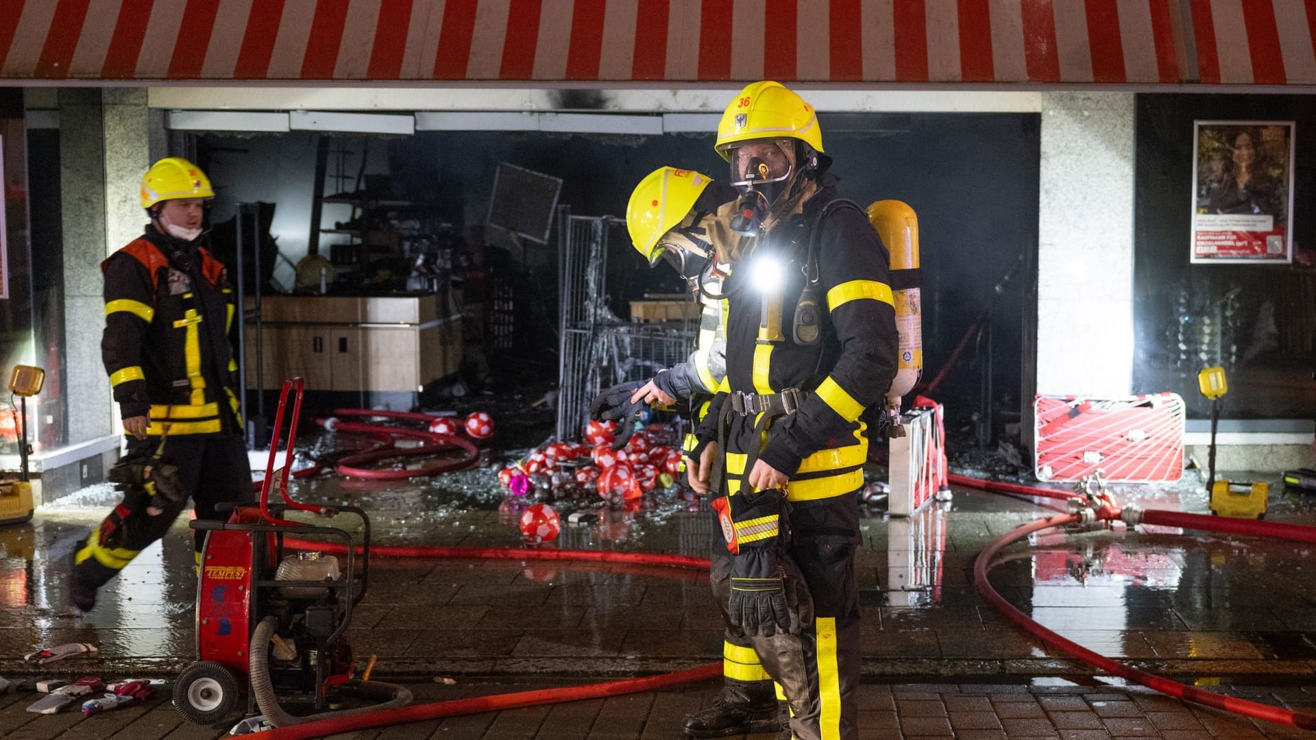 Die Feuerwehr ist bei einem Brand in einem Kaufhaus im Frankfurter Stadtteil Höchst im Einsatz. Drei Feuerwehrleute stehen vor dem Woolworth-Markt, der durch das Feuer zerstört wurde.