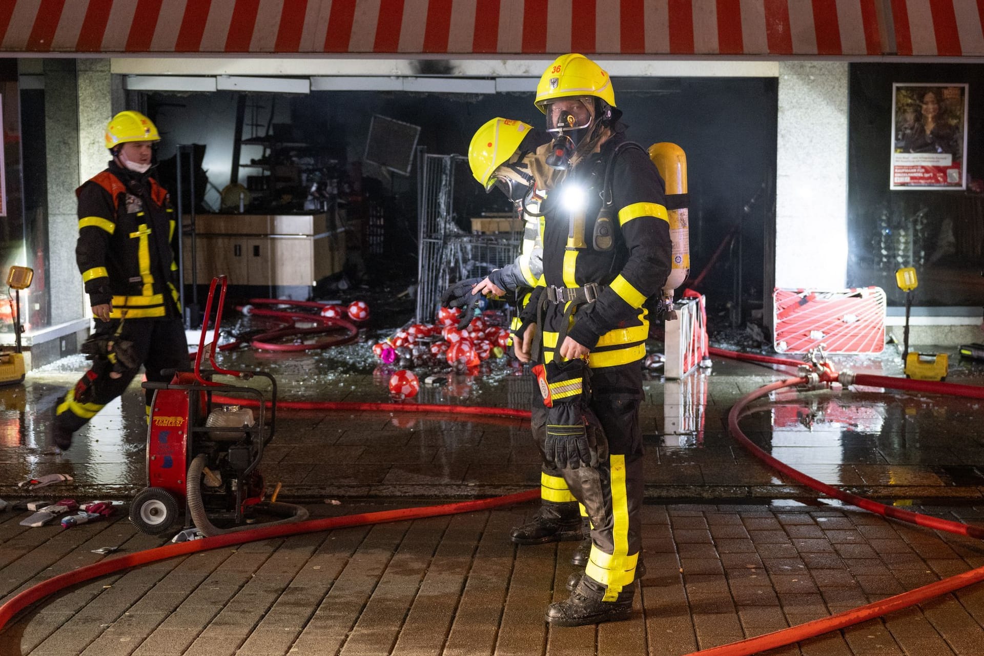 Die Feuerwehr ist bei einem Brand in einem Kaufhaus im Frankfurter Stadtteil Höchst im Einsatz. Drei Feuerwehrleute stehen vor dem Woolworth-Markt, der durch das Feuer zerstört wurde.