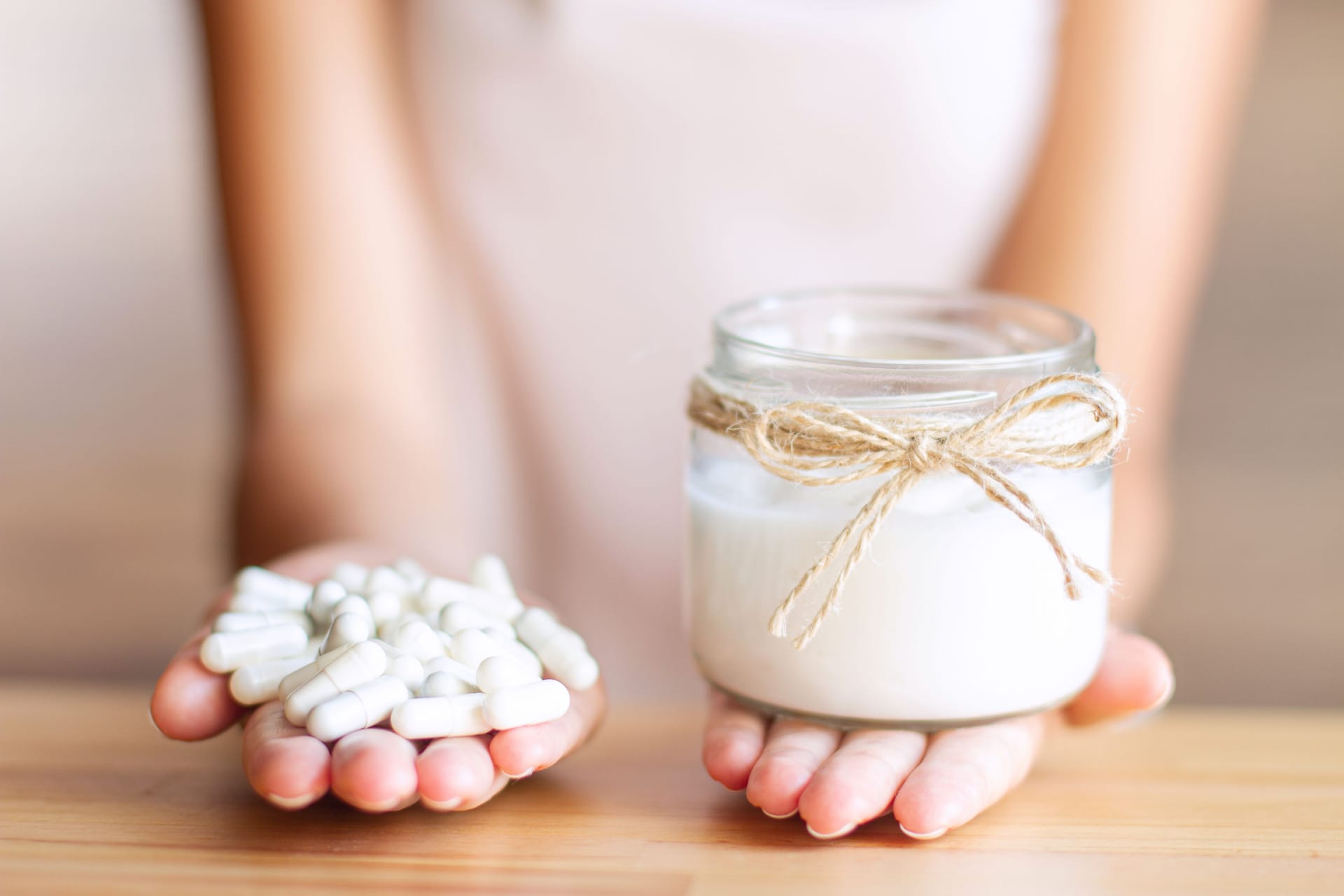 Frau mit Tabletten in der einen und Joghurt in der anderen Hand (Symbolbild): Probiotika sollen gut für die Verdauung sein.