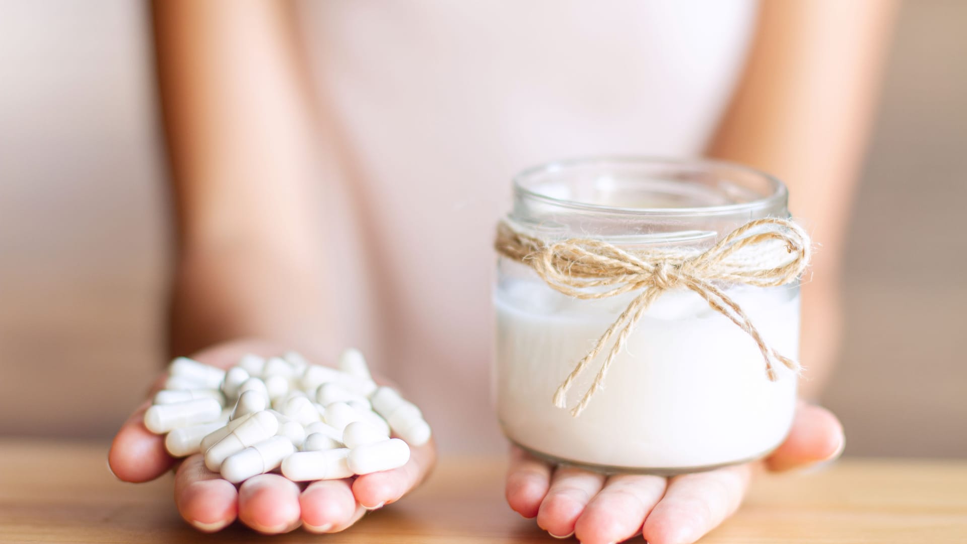 Frau mit Tabletten in der einen und Joghurt in der anderen Hand (Symbolbild): Probiotika sollen gut für die Verdauung sein.