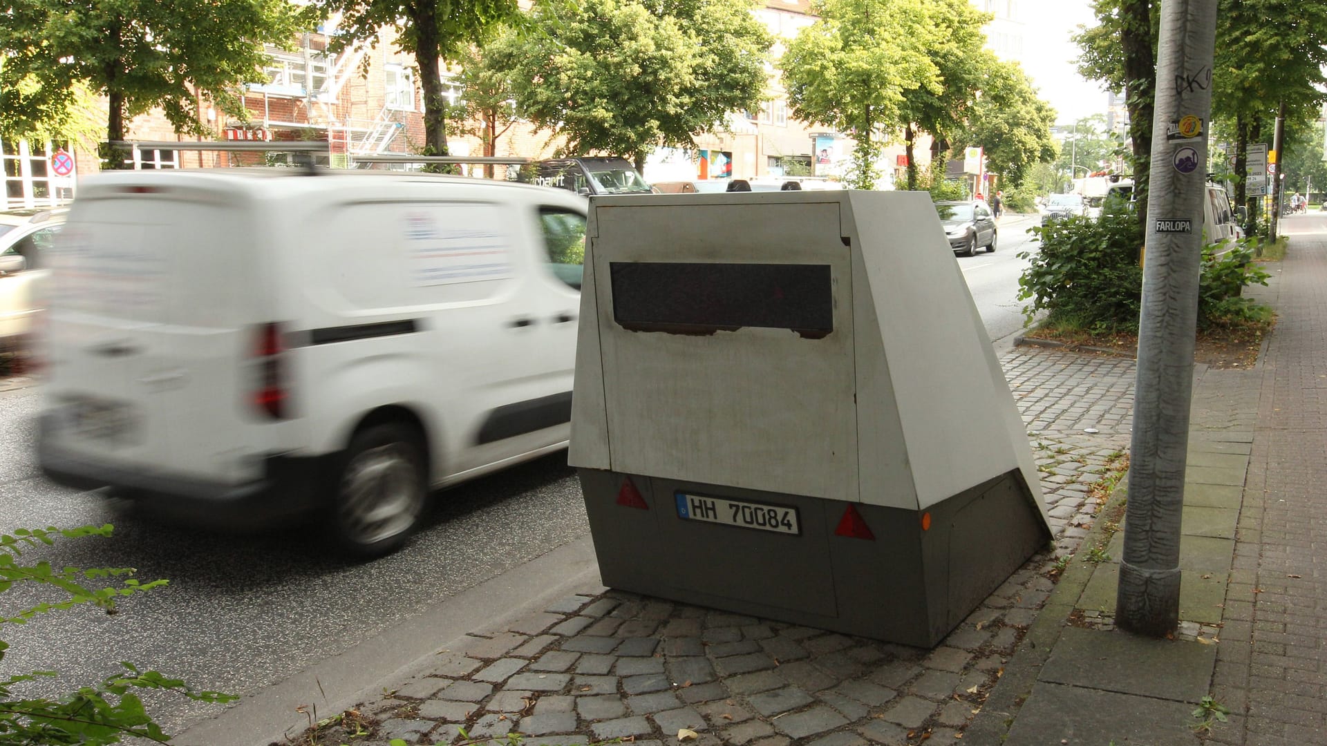 Ein mobiler Blitzer auf einem Parkplatz an einer Straße (Symbolbild): Immer wieder werden die grauen Messanhänger beschädigt oder sabotiert.