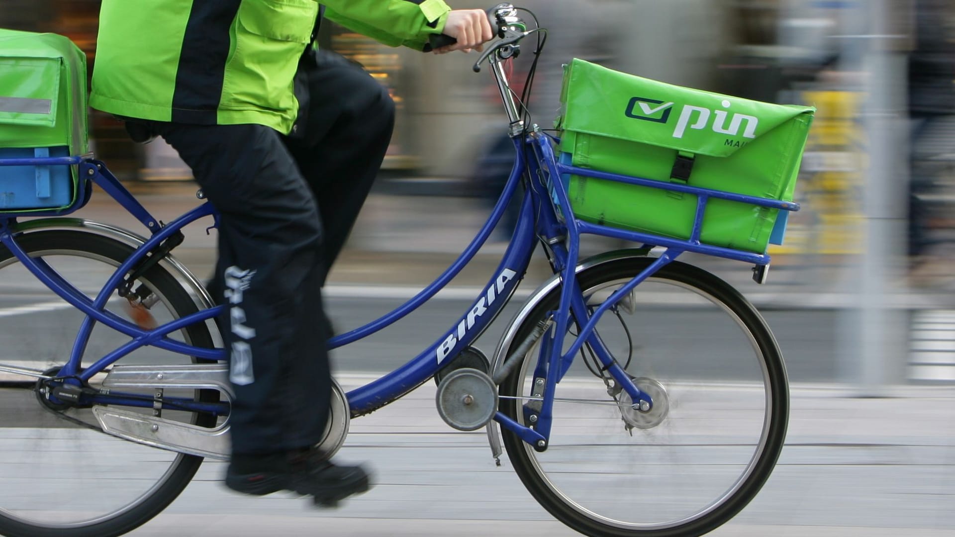 Briefzusteller des Dienstleisters Pin Mail auf einem Fahrrad