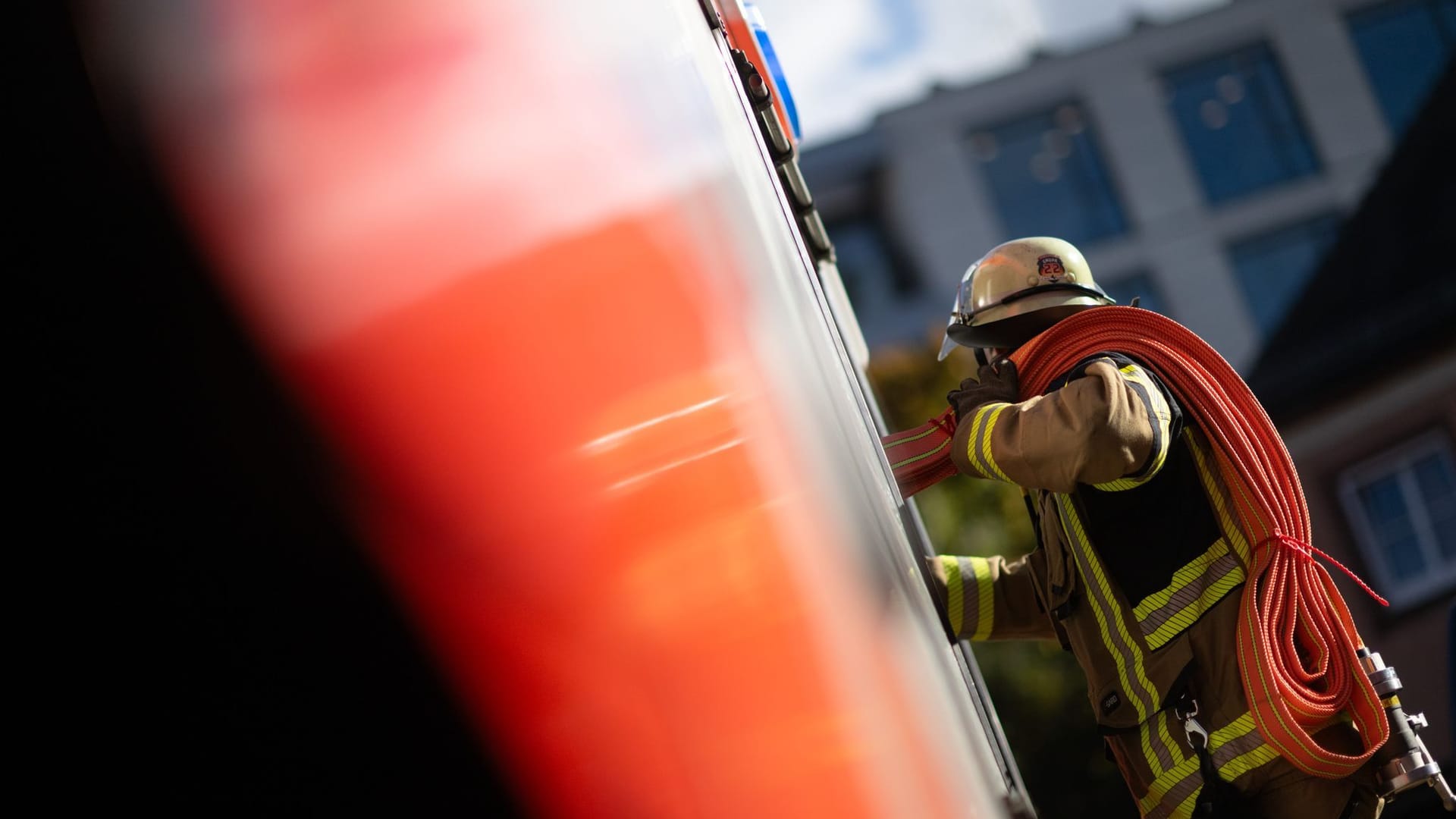 Ein Feuerwehrmann nimmt einen Schlauch aus einem Einsatzfahrzeug