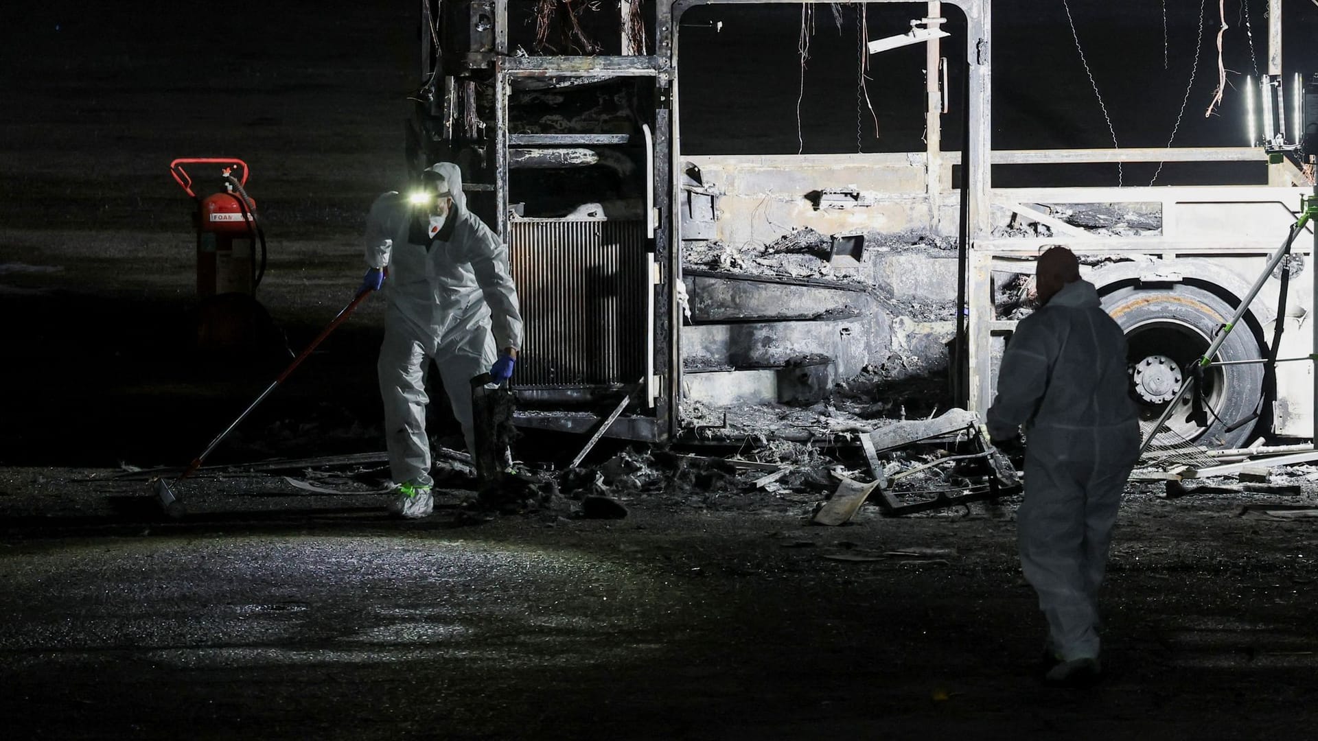 Sicherheitskräfte untersuchen einen der explodierten Busse.