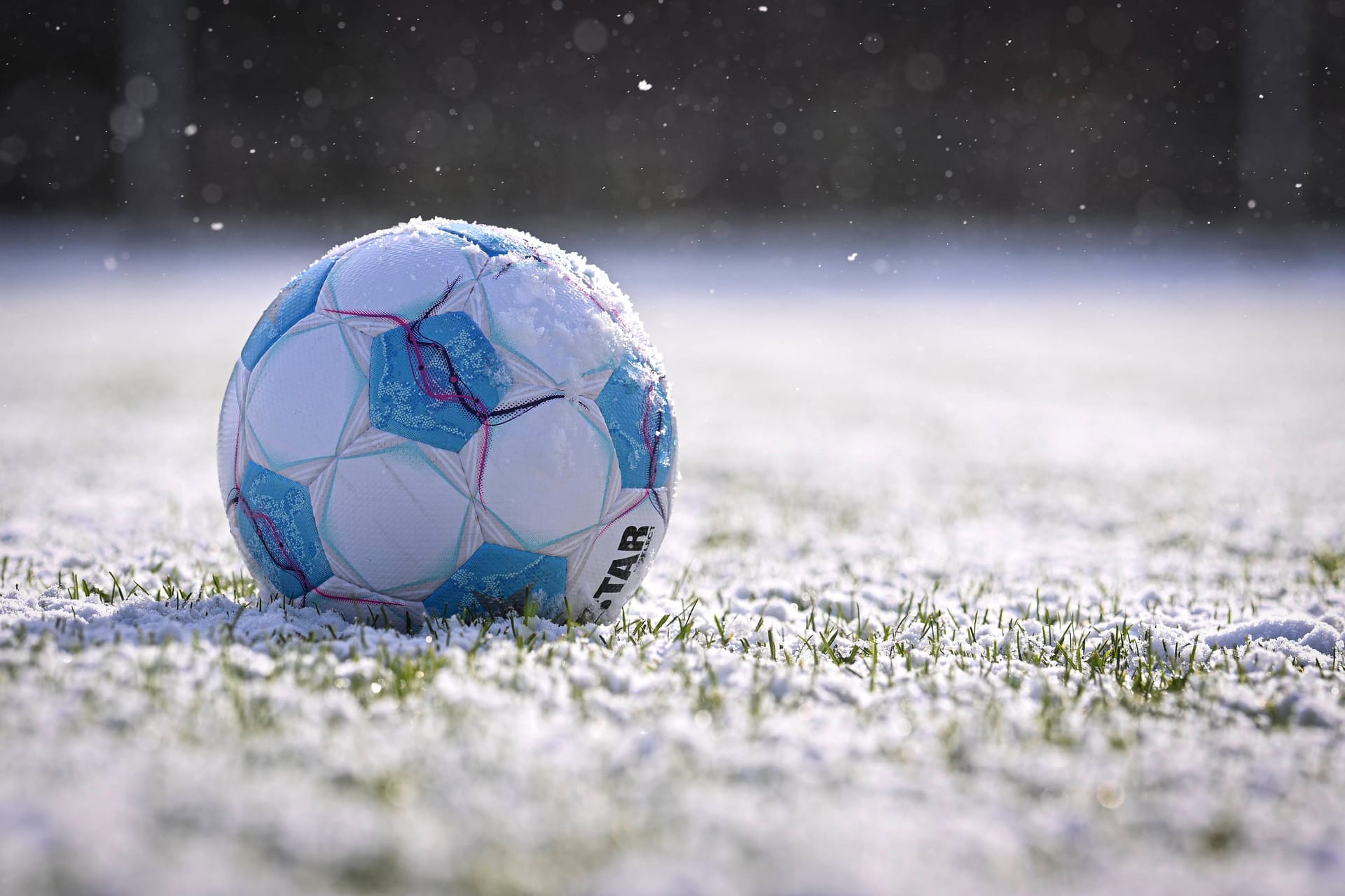 Ein Fußball auf schneebedecktem Rasen (Archivbild): In Berlin finden im Amateurbereich keine Spiele statt.