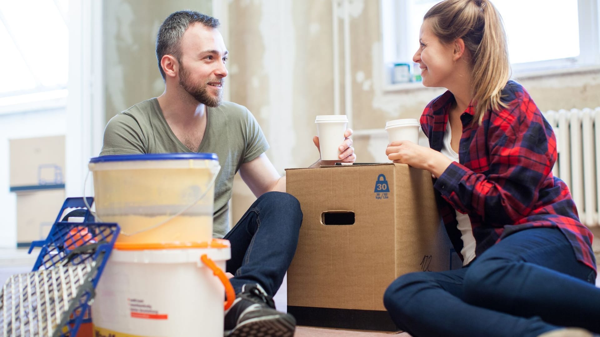 Paar sitzt mit Umzugkisten in einer Wohnung