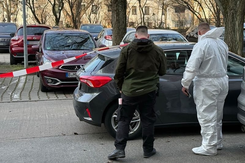 Zwei Beamte der Spurensicherung stehen vor einem Auto, das mit Absperrband gesichert ist: Ein Mann ist nach einer Gewalttat in Marzahn gestorben.