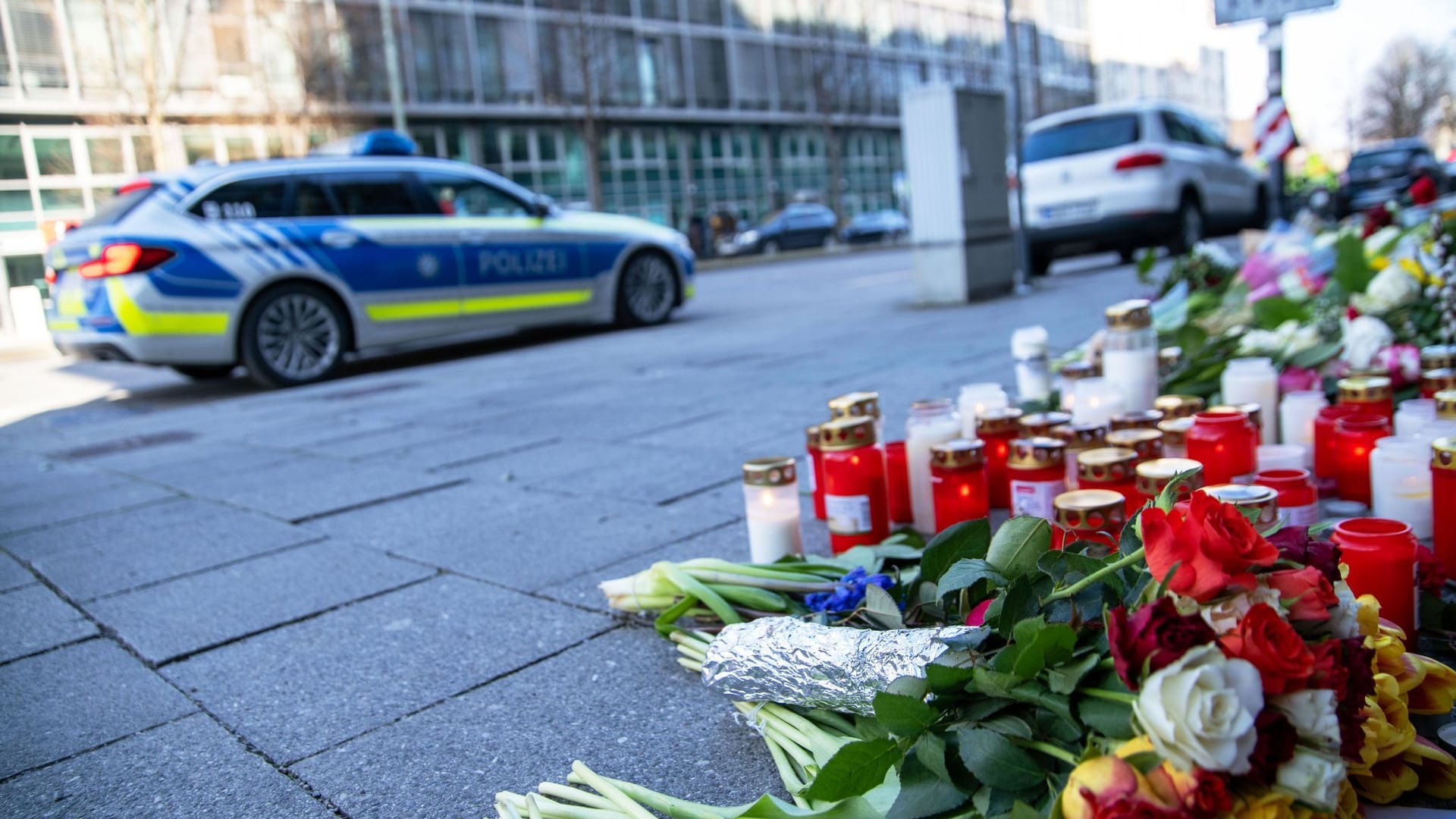 Ein Einsatzfahrzeug der Polizei steht neben Blumen und Kerzen nahe der Stelle in der Innenstadt, wo am 13.02.2025 ein Auto in eine Gruppe von Demonstranten gefahren war.