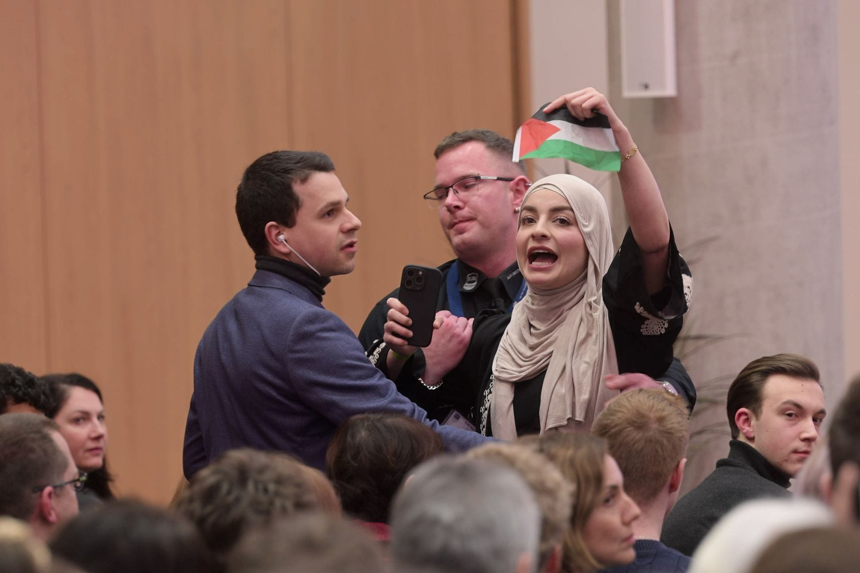 Eine pro-palästinensische Fragestellerin wird bei einem Bürgerdialog mit Bundeskanzler Scholz aus dem Campus geleitet.