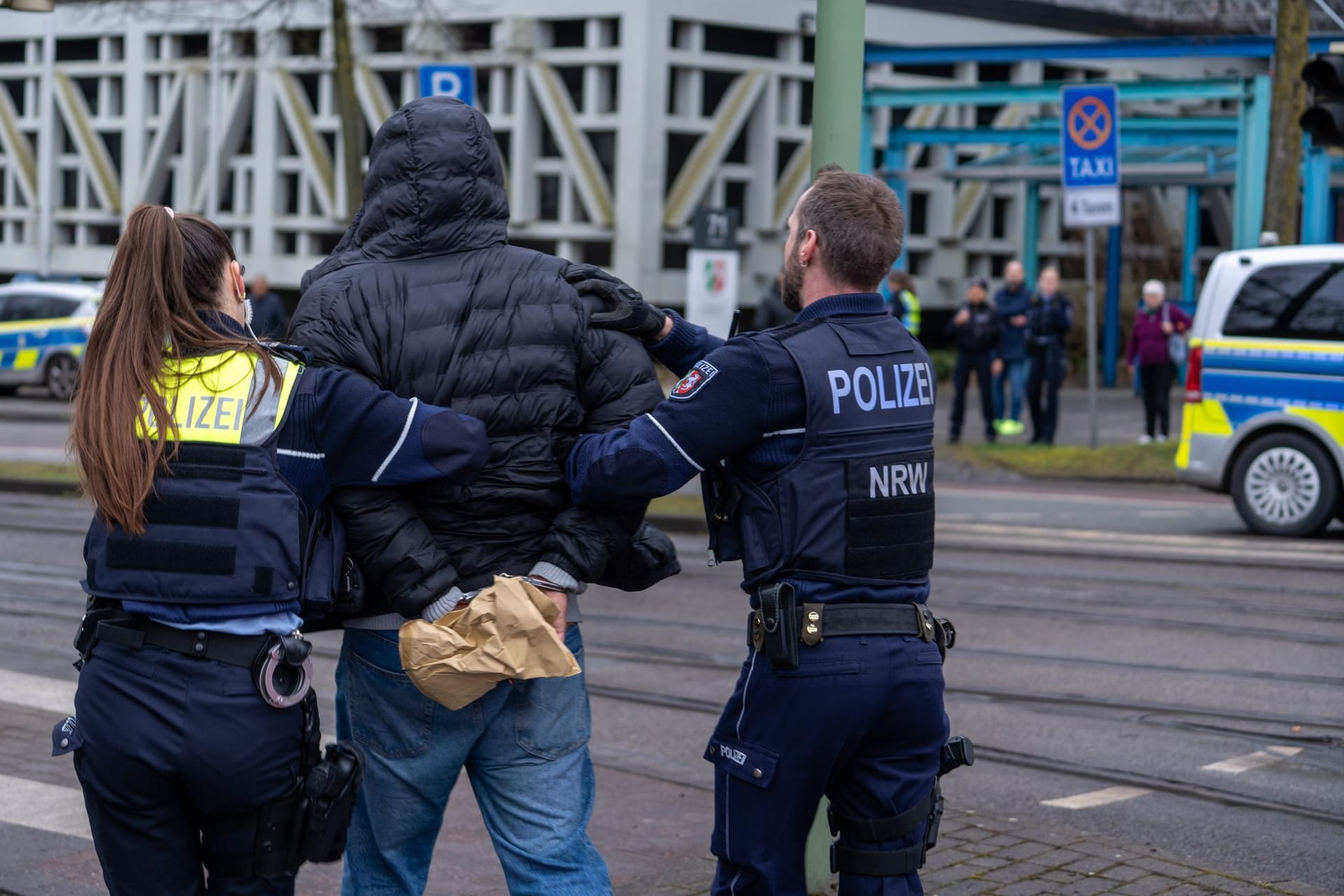 Bielefeld: Einsatzkräfte der Polizei führen einen Mann in der Nähe von einem Tatort in Handschellen ab.