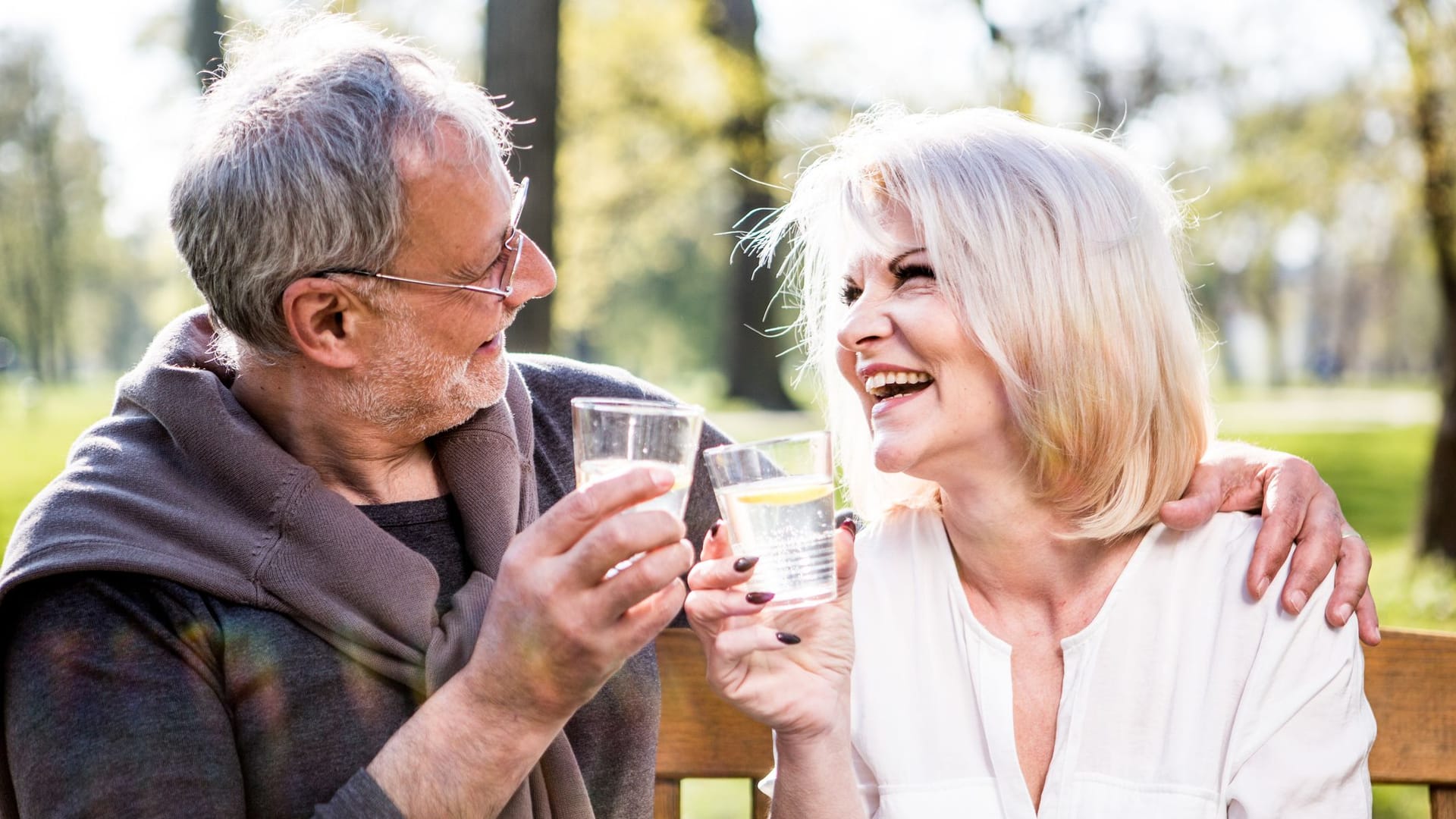 Rentnerpaar im Garten trinkt Wasser