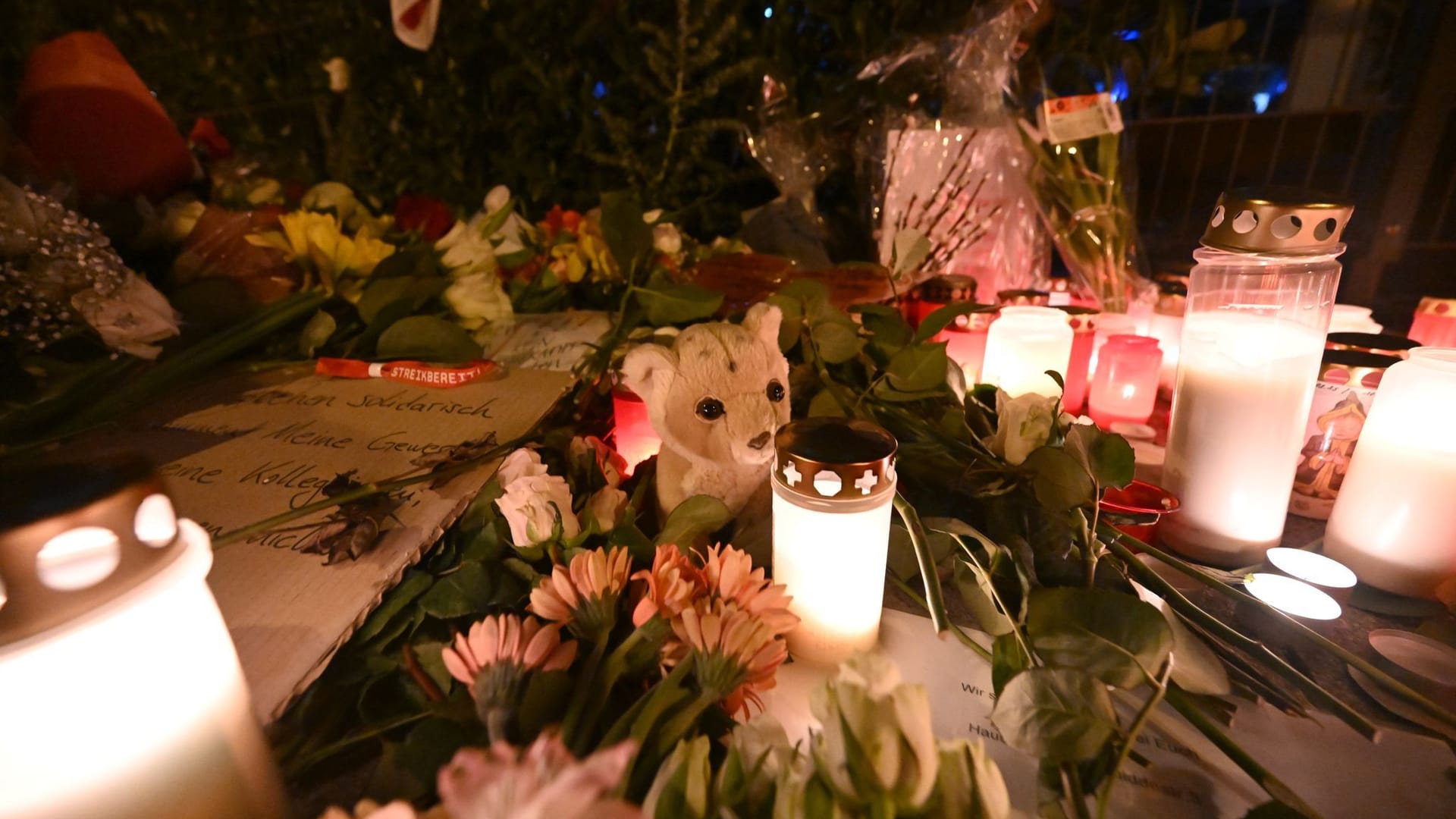 Blumen, Kerzen und ein Teddybär liegen auf dem Gehweg in der Nähe der Stelle, wo am 13.02.2025 ein Auto in eine Gruppe von Demonstranten gefahren war.