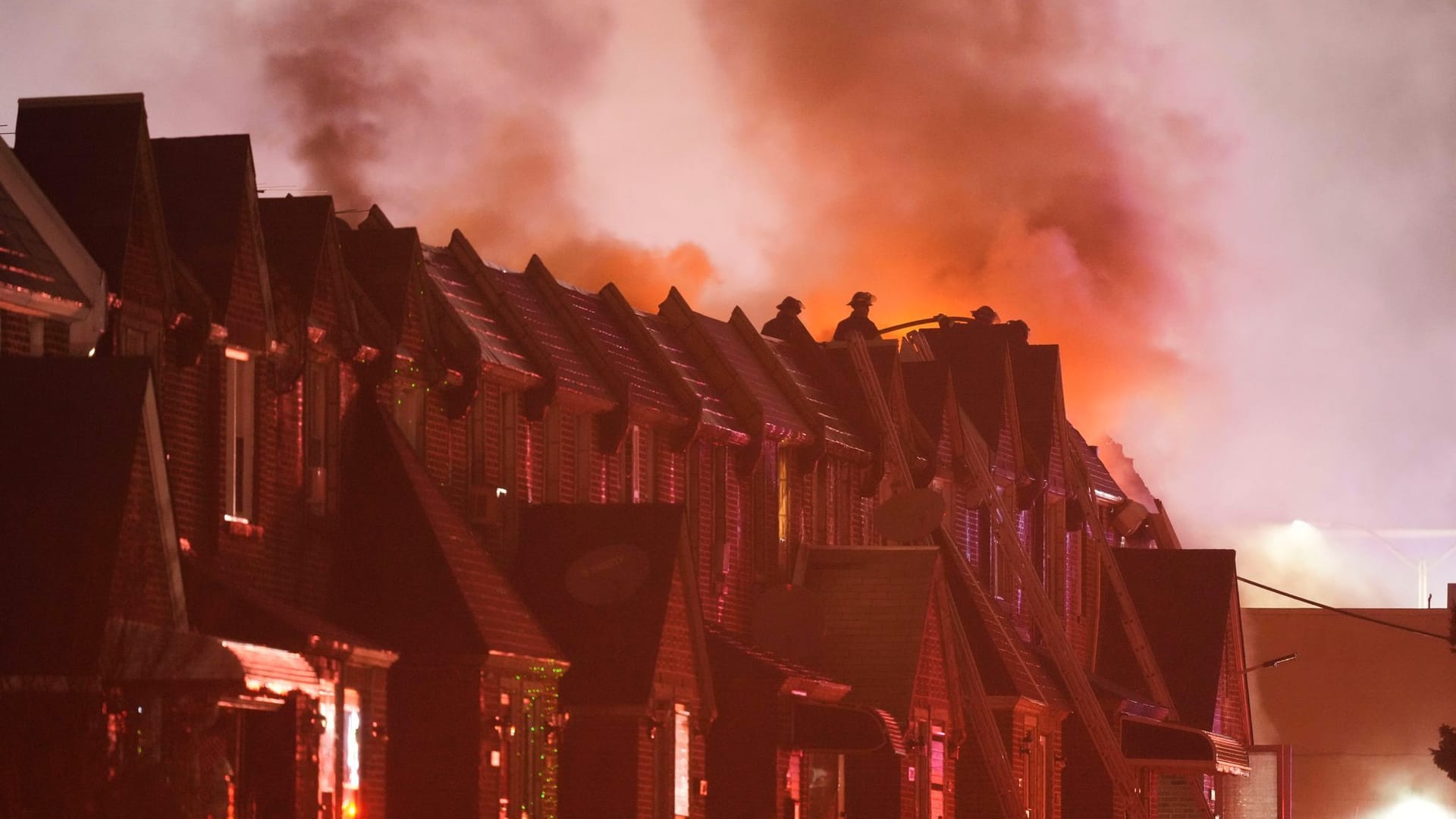 Feuerwehrleute stehen auf den Dächern von Häusern vor der Absturzstelle.