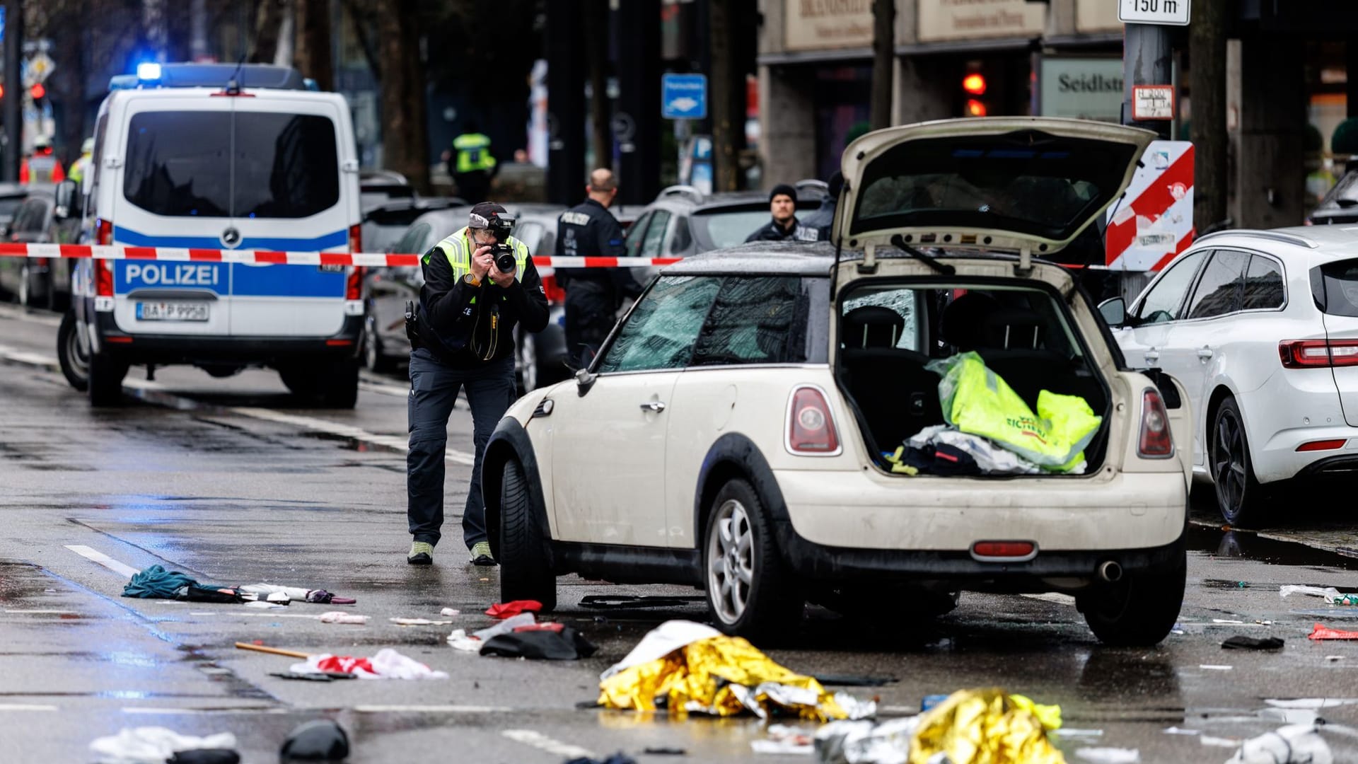 Ein Polizist fotografiert ein Auto am Einsatzort. In der Münchner Innenstadt ist ein Fahrzeug in eine Menschengruppe gefahren.