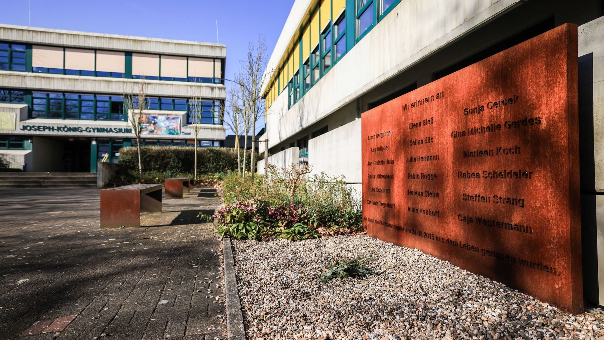 Am Joseph-König-Gymnasium steht eine Gedenktafel direkt am Schulhof, davor wird in den Pausen getobt und gelacht - ein Symbol dafür, dass die Toten weiterhin Teil der Schule sind.