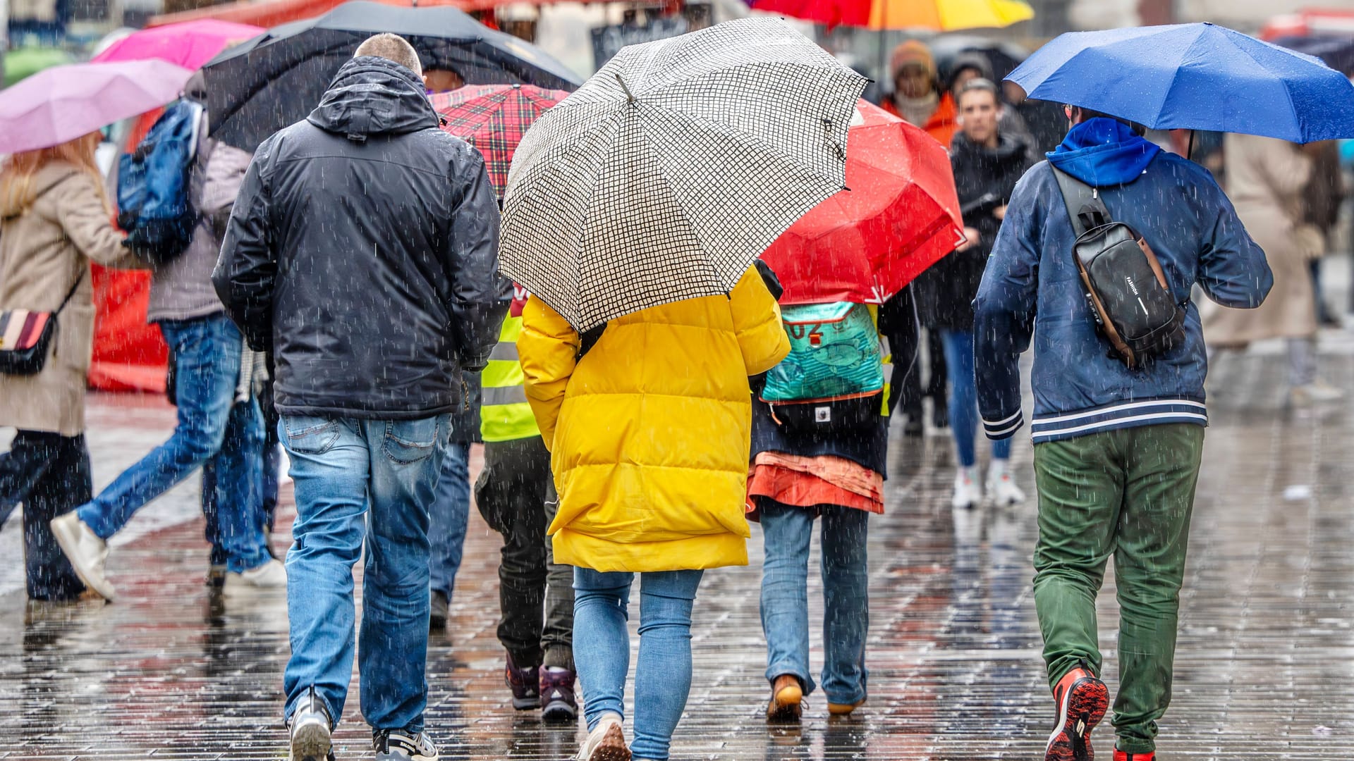 Menschen laufen mit Regenschirmen durch München (Archivbild): Vor allem am Mittag könnte es am Sonntag stellenweise nass werden.