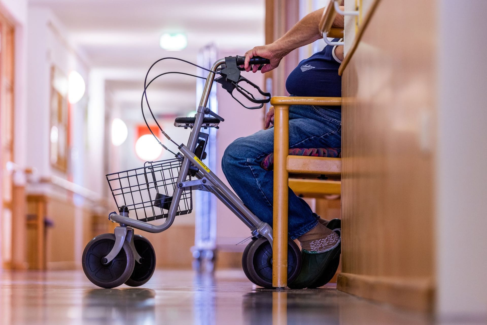 Bewohner sitzt mit seinem Rollator auf dem Flur eines Pflegeheims