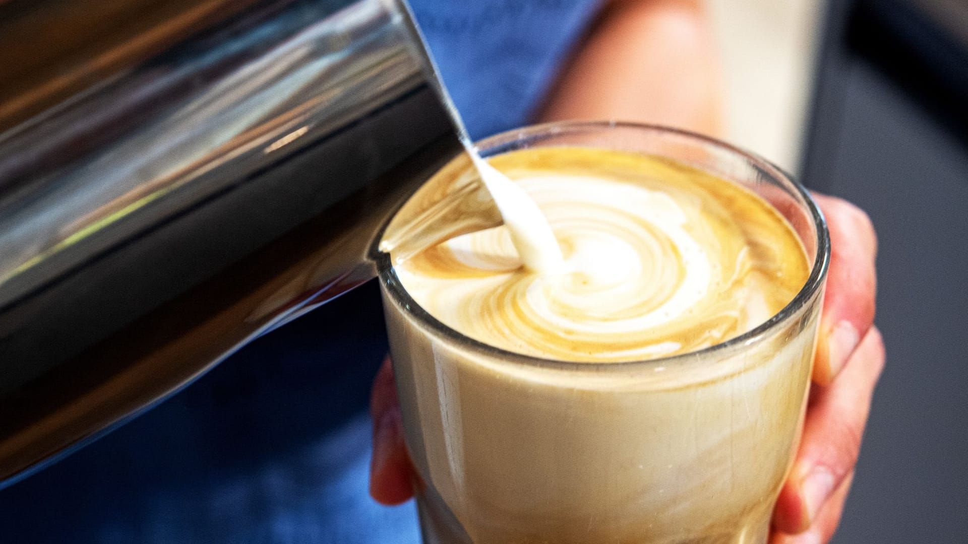 Milch wird in einen Kaffee gegossen