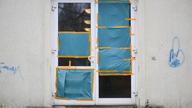 Planen decken an einer Unterkunft für Geflüchtete die beschädigten Scheiben einer Tür ab. Das Übergangswohnheim für Asylsuchende wurde in der Nacht des vergangenen Samstags angegriffen.