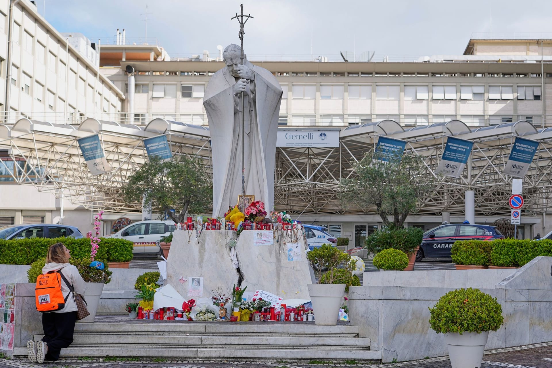 Eine Frau kniet vor der Statue von Papst Johannes Paul II., während sie für Papst Franziskus vor der Klinik Agostino Gemelli betet.