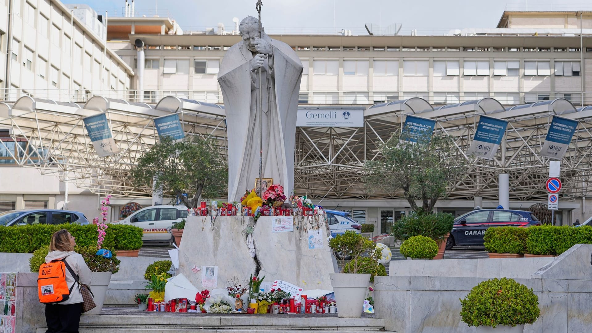 Eine Frau kniet vor der Statue von Papst Johannes Paul II., während sie für Papst Franziskus vor der Klinik Agostino Gemelli betet.